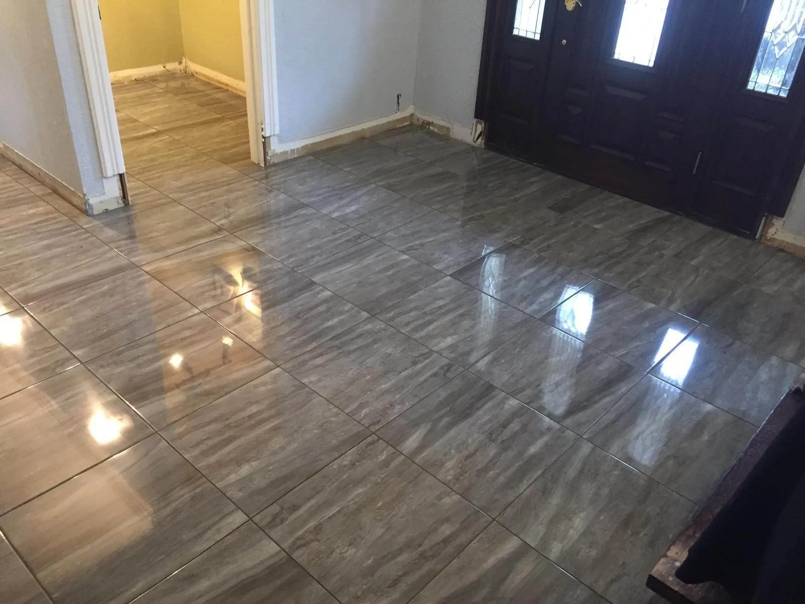 Large-format polished grey porcelain tile floor installed in a Long Island entryway