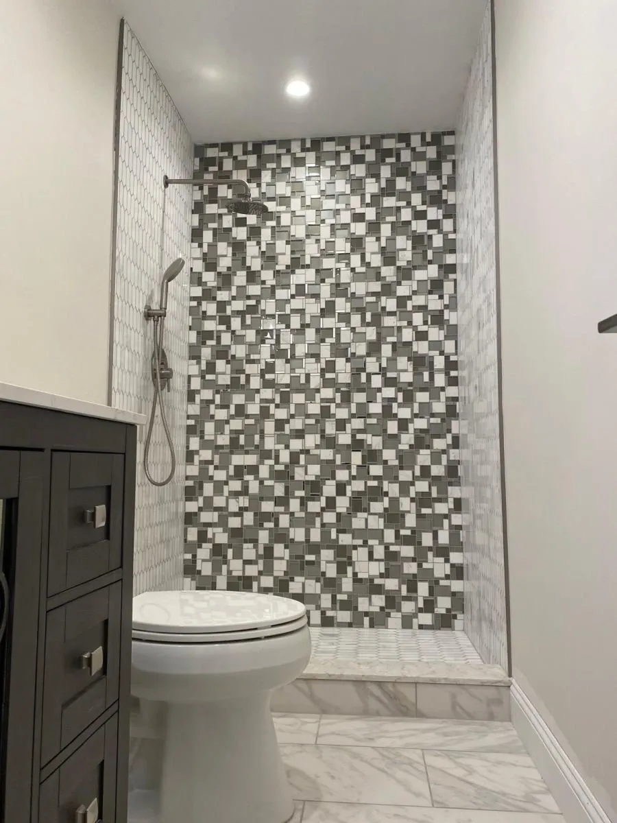 Ducha de azulejo en mosaico con vanidad de madera oscura