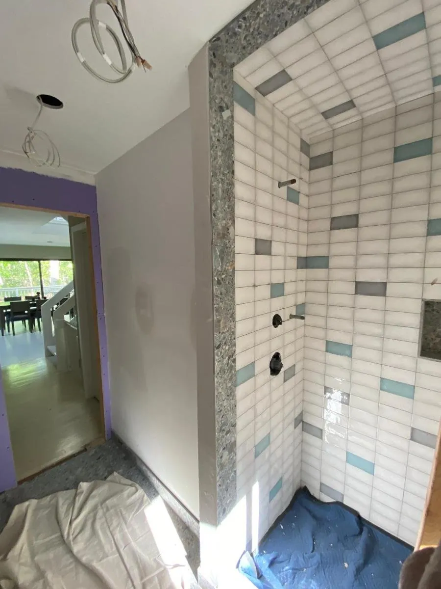 Tiled shower enclosure in progress with a decorative accent band
