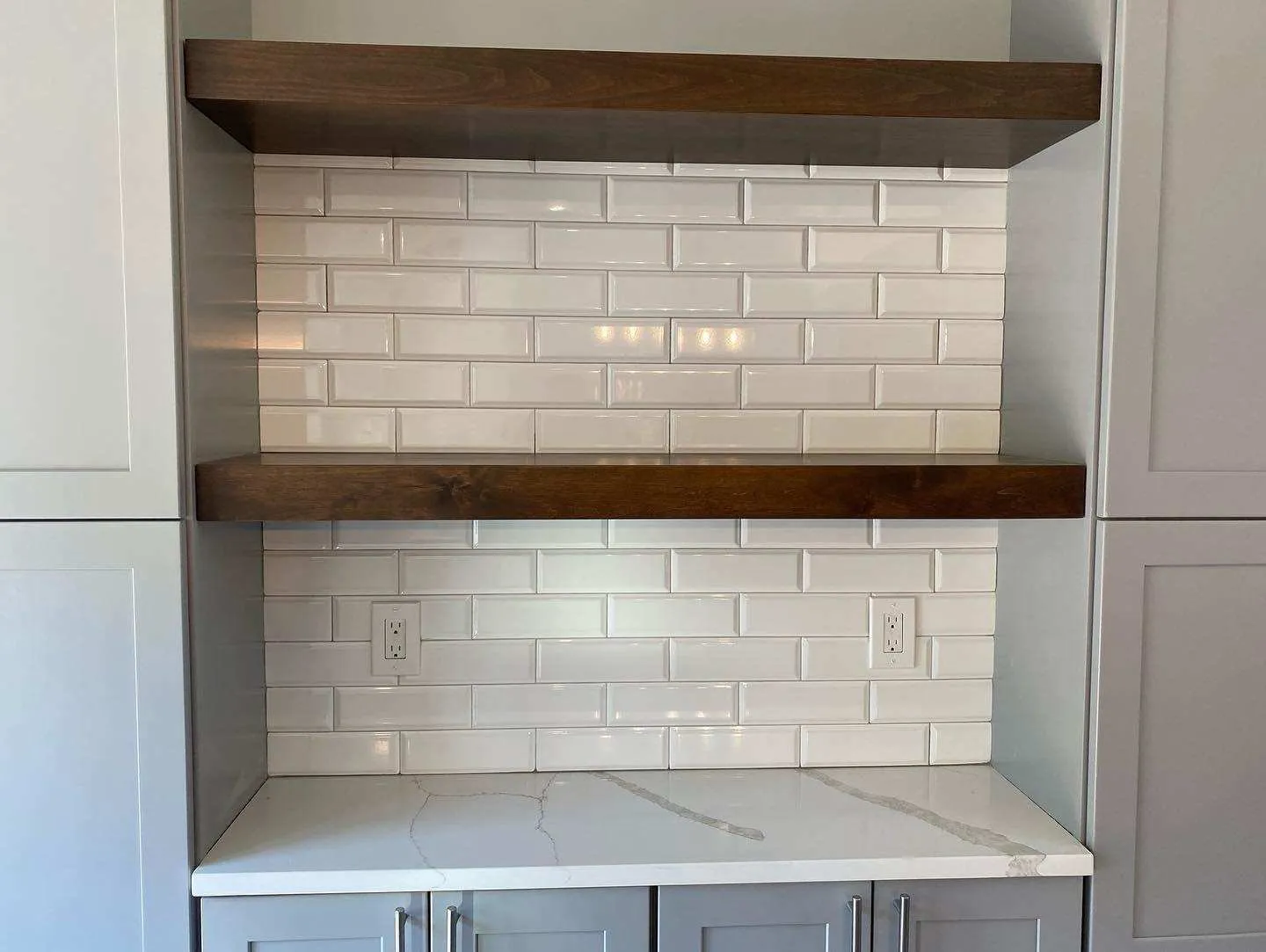 Cocina con backsplash blanco tipo subway, encimera de mármol y repisas flotantes de madera